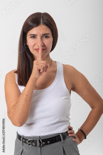 Fotografie Young woman with finger to her lips asking for quiet and discretion, conveying s