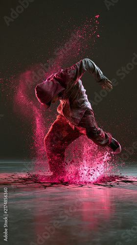 A dancer in mid-performance, surrounded by a cloud of pink powder. The dancer's body is angled dynamically, capturing a moment of intense movement and artistic expression