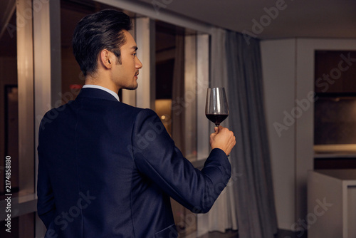 Fotografie Elegant businessman tasting red wine in modern interior