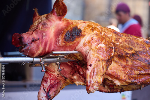 Roasted whole pig cooking on a spit at a medieval market in Puebla de Sanabria