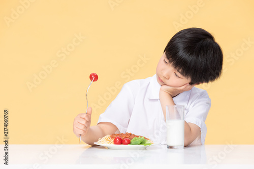 Canvas Print Young boy showing loss of appetite at mealtime with pasta and milk
