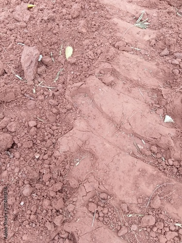 Texture of clumpy red soil with a heavy agricultural vehicle wheel print.