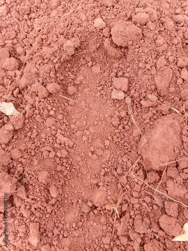 Close-up texture of dry, clumpy red earth or clay soil.