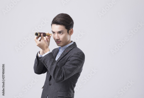 Quadro su tela Young businessman looking through spyglass in studio