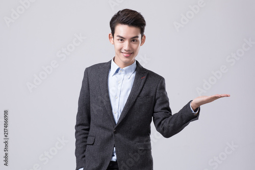 Smiling young businessman presenting with open palm