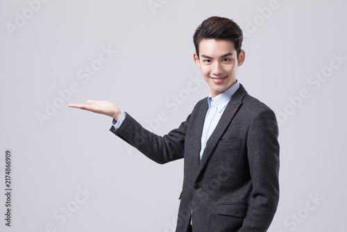 Smiling businessman presenting empty palm with copy space