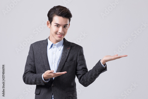 Smiling young businessman presenting empty copy space with open hands