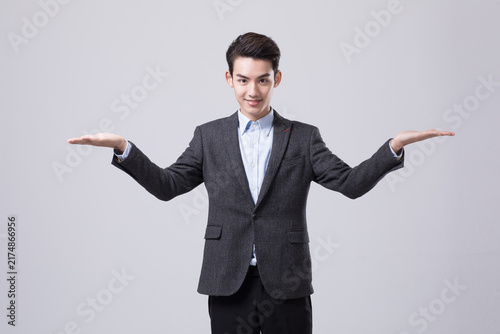 Young businessman presenting with open hands in studio