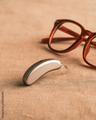 Hearing aid and glasses on a fabric background