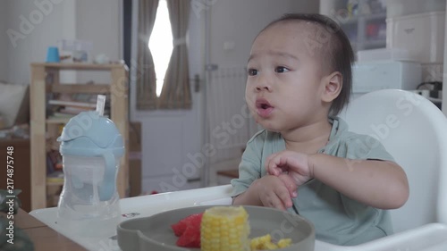 A cheerful infant sitting in a high chair, expressing excitement while eating a colorful meal. The scene captures the joy of mealtime and showcases a variety of healthy foods.