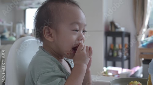 A playful child in a high chair expresses joy during snack time, surrounded by a cozy kitchen atmosphere.