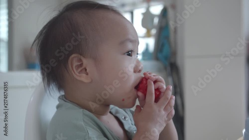 A close-up shot of a young child enjoying a piece of food, capturing their curious and focused expression. The image highlights the innocence and wonder of childhood moments during mealtime.