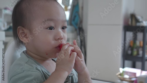 A joyful child is seen sitting in a high chair, happily snacking and exploring their surroundings. The image captures the innocence and curiosity of early childhood, making it a delightful scene for a
