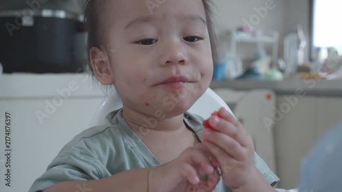 A young child explores and enjoys a snack, showcasing a moment of curiosity and delight. The setting highlights a casual dining environment, capturing the essence of childhood and the joy of eating.