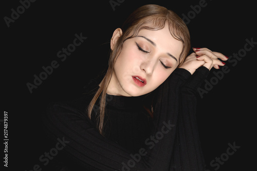 Bild auf Leinwand Moody portrait of young woman with closed eyes on black background