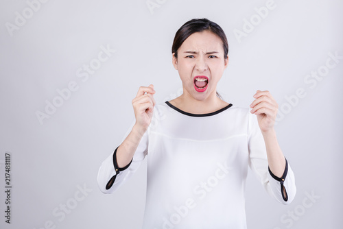 Obraz na płótnie Angry young woman shouting with clenched fists in studio portrait