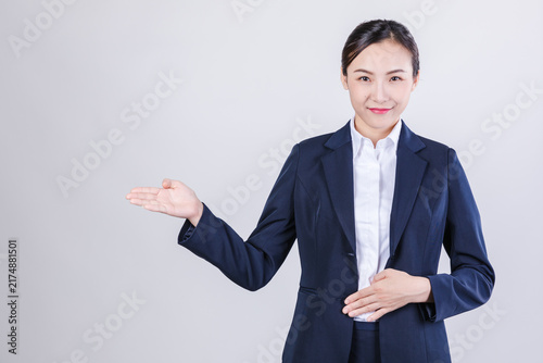 Photography Smiling businesswoman presenting with open hand gesture on light background