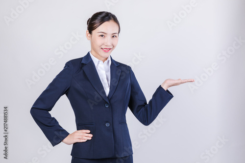 Photography Smiling businesswoman in suit presenting with open hand in studio