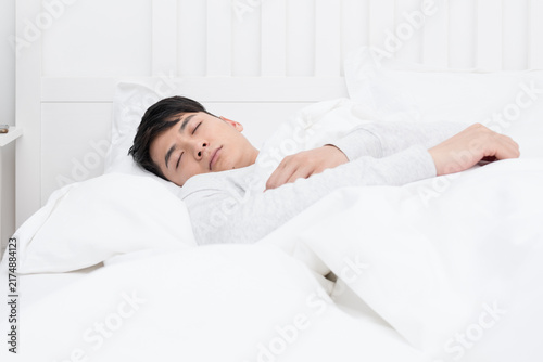 Foto Young man sleeping peacefully in white bed at home