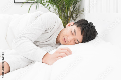 Bild auf Leinwand Young man sleeping peacefully in bed at home