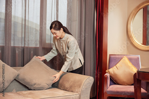 Foto Housekeeper Tidying Sofa Cushions in Hotel Suite Living Room