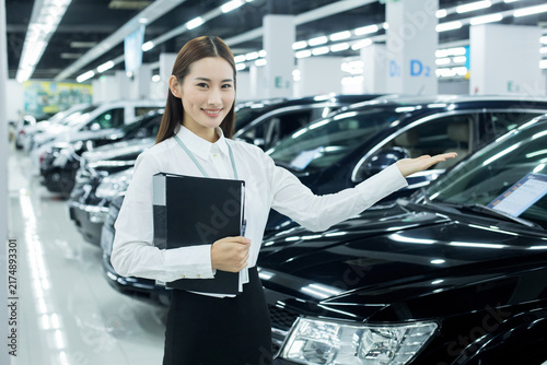 Foto Smiling car saleswoman presenting vehicle in dealership showroom