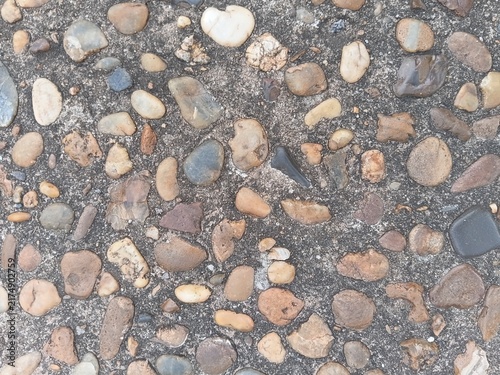 Texture of a washed pebble walkway. Colorful river stones embedded in a concrete floor