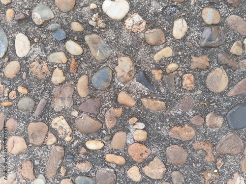 Texture of a washed pebble walkway. Colorful river stones embedded in a concrete floor