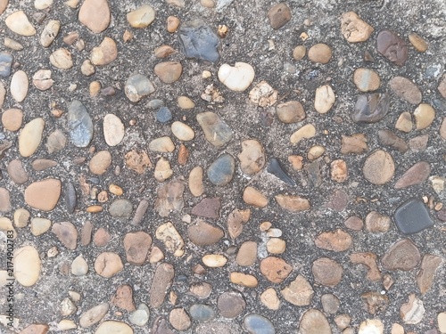 Texture of a washed pebble walkway. Colorful river stones embedded in a concrete floor
