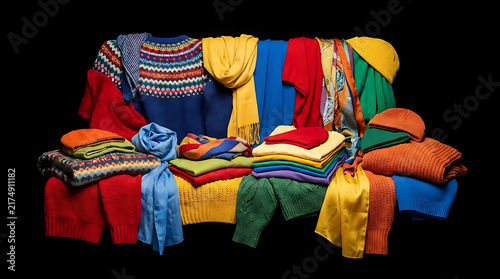 Colorful wool sweaters stacked neatly on a couch