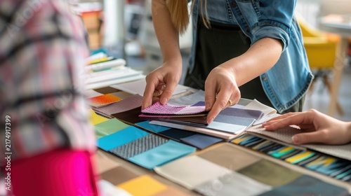 Interior designer choosing fabric samples for a project on a table in a studio with Two individuals examine colorful fabric swatches laid out table during professional design consultation assortment