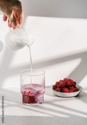 Fresh raspberry puree with milk on a light background.