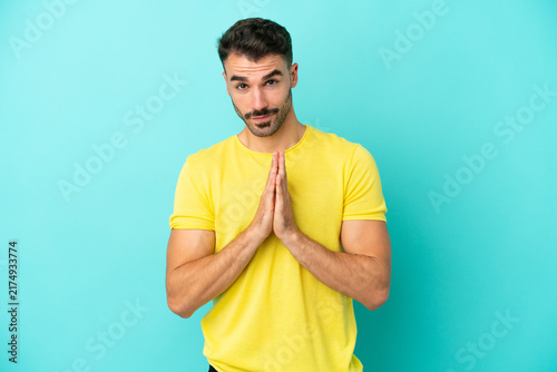 Konstfotografi Young caucasian man isolated on blue background keeps palm together