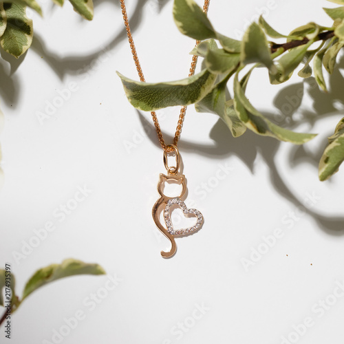 Obraz na płótnie Delicate Gold Cat Necklace with Heart Pendant Surrounded by Greenery, Perfect fo