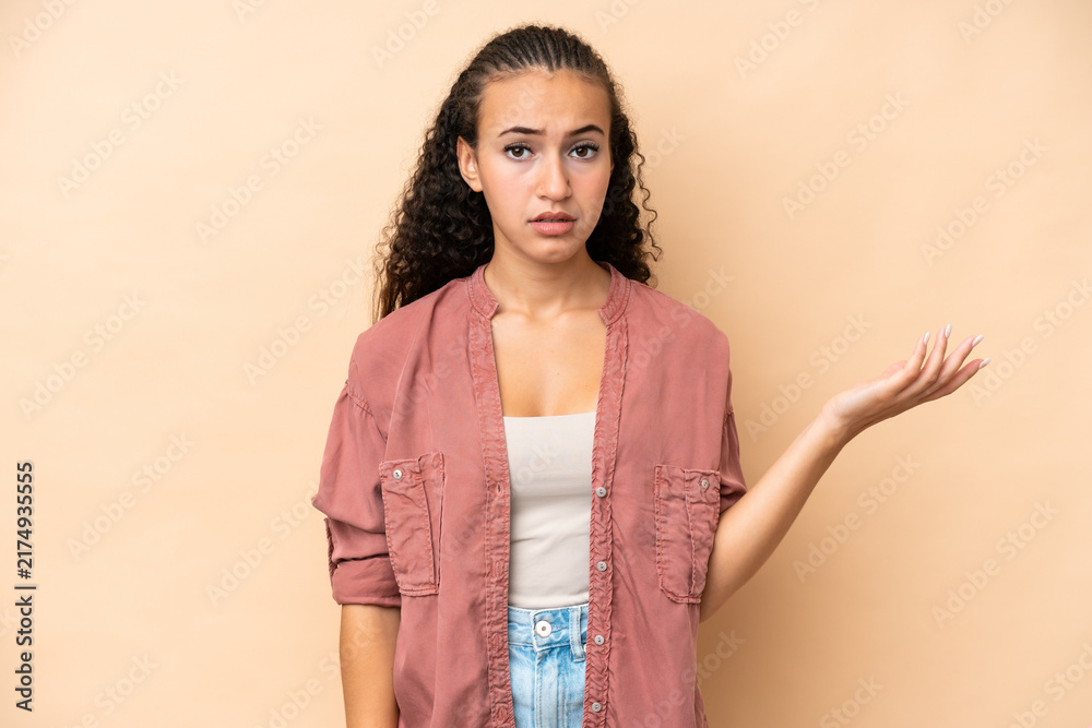 Obraz premium Young woman isolated on beige background making doubts gesture