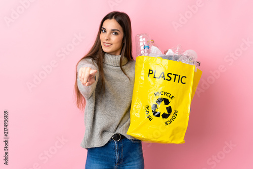 Cuadro en lienzo Young caucasian woman holding a bag full of plastic bottles to recycle isolated