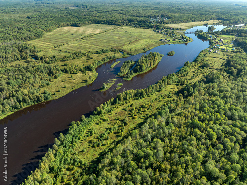 Aerial view of a winding river meandering through green taiga forest and fields near Kindasovo village in Karelia, Russia