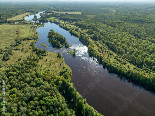 Aerial view of a winding river meandering through green taiga forest and fields near Kindasovo village in Karelia, Russia
