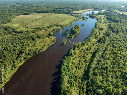 Aerial view of a winding river meandering through green taiga forest and fields near Kindasovo village in Karelia, Russia