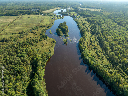 Aerial view of a winding river meandering through green taiga forest and fields near Kindasovo village in Karelia, Russia