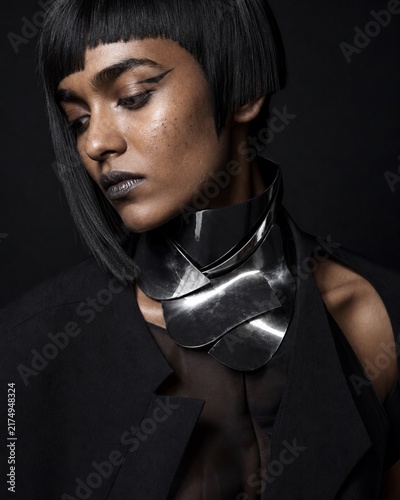 Striking Portrait of a Woman with Avant-Garde Jewelry: A dramatic portrait of a woman with a sharp bob haircut and striking makeup, adorned with a unique, architectural silver neckpiece.