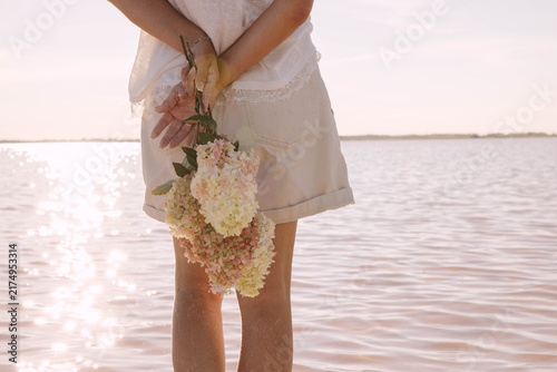 womans hands in shallow lake with flower bouquet, peaceful waterside, sunny summer evening with glowing reflections, mindfulness, solitude and nature, travel tourism, wellness retreat