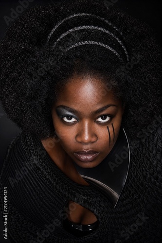 Mysterious Woman with Intense Gaze: A striking portrait of a woman with bold, dramatic makeup and an imposing braided hairstyle, conveying a sense of mystery and power.