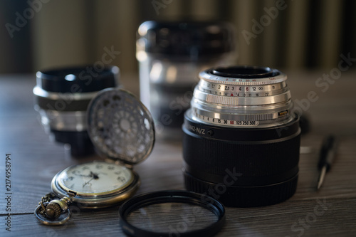 Fotografie set of vintage photo lens on a wooden table and retro pocket watch