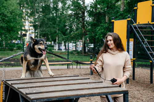 Fotografie dog agility training, young caucasian woman instructor trains cute clever mongre