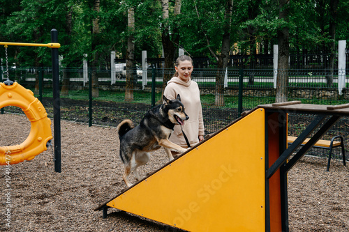 Obraz na płótnie dog agility training, young caucasian woman instructor trains cute clever mongre