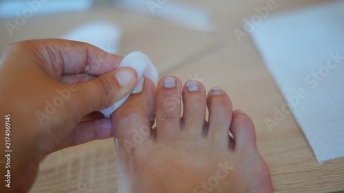 Close-up of a person wiping toenails with a cotton pad during a home pedicure. The image represents cleansing, nail preparation, personal hygiene, and everyday self-care.
