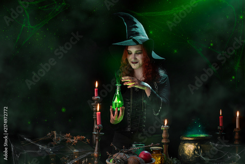 Obraz na plátne Witch conjuring a love potion, cooking up love, casts a spell, bottle with glowing poison in her hands