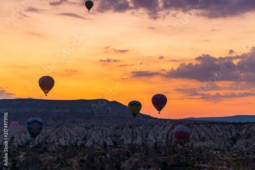 Hot air balloons flying over rocky valley at sunset. Hot air ballooning represents freedom exploration dream.
