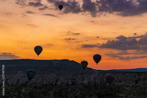 Hot air balloons flying over rocky valley at sunset. Hot air ballooning represents freedom exploration dream.